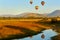 Hot air balloons with tourists above the Pilanesberg reserve. Three hot air balloons, decorated safari motifs against blue sky,