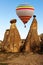 Hot air baloon flying over spectacular stone cliffs in Cappadocia