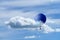 Hot air blue ballon against blue sky with white fluffy clouds an