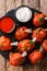 Hot appetizer Lollipops fried red chicken wings served with sauces close-up on a slate board. Vertical top view