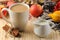 Hot autumn drink, coffee or cocoa, with yellow leaves and decorative pumpkins, acorns and apples on a natural wooden table. autumn