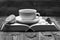 Hot beverage with sugar cubes placed on open book on wooden background. Warm drink and home relax concept. Tea cup on