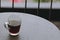 Hot black coffee in clear glass on the table at balcony. Morning cup of hot coffee on the table