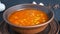 Hot boiled red tomato soup with corn with steam in a brown clay plate in a rustic style