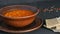 Hot boiled red tomato soup with corn with steam in a brown clay plate in a rustic style