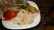 Hot boiled rice and chopped tomatoes with sliced onions lie on white plate on wooden kitchen board.