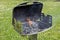 An hot burning empty charcoal barbecue with open fire. Preparing delicious outdoor barbecue on a green meadow with daisies on a