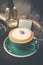 Hot cappuccino in green coffee cup on wood table