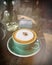 Hot cappuccino in green coffee cup on wood table