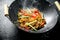 Hot cellophane noodles in a frying pan wok with bell peppers, cucumber and carrots