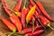 Hot chili peppers piled in a wooden bowl close-up vegetable background