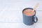 Hot chocolate in a blue-grey ceramic mug with wooden stirrer  on white painted wood. Space for text
