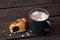 Hot chocolate with marshmallows in a blue-grey ceramic mug next to a half of chocolate croissant isolated on rustic dark brown