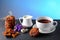 Hot chocolate and milk, cup of cocoa, chocolate cookies, almonds, flowers on a shale board on bright blue background, place to cop