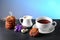 Hot chocolate and milk, cup of cocoa, chocolate cookies, almonds, flowers on a shale board on bright blue background, place to cop