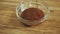 Hot chocolate pouring into glass bowl standing on wooden table.