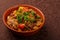 hot cholent sprinkled with green onions in a clay plate on a tablecloth.