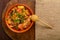 hot cholent sprinkled with green onions on a wooden stand with a spoon on a set Shabbat table.