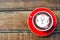 Hot cocoa and face cat milk foam in the red cup on wood background