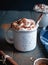 Hot cocoa with whipped cream and cinnamon stick on dark background