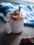 Hot cocoa with whipped cream and cinnamon stick on dark background