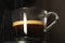 Hot coffee flow to a cup on espresso machine in black background.