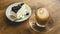 Hot coffee latte and blueberry cheesecake on wooden table.