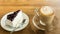 Hot coffee latte and blueberry cheesecake on wooden table.
