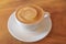 Hot coffee latte cappuccino cup with spiral milk foam on wood ta