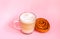 Hot coffee latte transparent glass cup on and sweet cinnamon roll on pink background