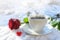 Hot coffee in a white cup served outdoors in the snow  decorated with a red rose and a little heart from glass on a sunny winter