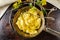 Hot corn porridge with sugar and butter on an old rustic pan and a metal vintage stand. Next to it is a sprig of flowering