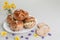 Hot cross buns on an oval plate, currant biscuits, with a vase of flowers