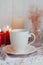 A hot cup of black tea  on a striped tablecloth, wax candles, a glass vase with decorative herbs on a white background