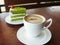 Hot cup of coffee cappuccino and layer green tea cake.