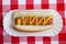 An hot dog with mustard on gingham