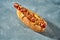 Hot dog with sausage, dry onions, cheddar and pickled cucumbers in a white bun on a gray background. Selective focus. American