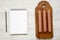 Hot dog sausages on wooden board, blank notepad with pencil over white wooden background, top view. Flat lay, overhead, from above