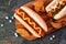 Hot dogs and potato wedges on wooden board, close up, top view