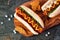 Hot dogs and potato wedges on wooden board, close up, top view