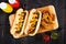 Hot dogs and potato wedges on wooden board, overhead scene