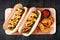 Hot dogs and potato wedges on wooden board, overhead view