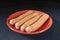 Hot dogs on table in red plate on black background