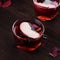 Hot drink with hibiscus red tea with apple, cinnamon and anise in two glasses on wooden background