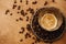 Hot espresso with foam in glass cup on vintage plate with aromatic roasted coffee beans on wooden table. Flat lay with copy space