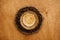 Hot espresso with foam in glass cup on vintage plate with aromatic roasted coffee beans on wooden table. Flat lay with copy space