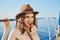 Hot european model eating strawberry while sitting on yacht under sun, wearing straw hat. Advertisement and vacation