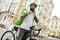 Hot and fast. Brutal bearded delivery man wearing helmet, looking aside while standing with his bicycle outdoors, ready