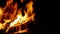 Hot fire and flames from wood logs burning in a fireplace, with dark background and copy space on right, in a relaxing closup clip