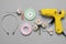 Hot glue gun, plastic headband and handicraft materials on grey background, flat lay